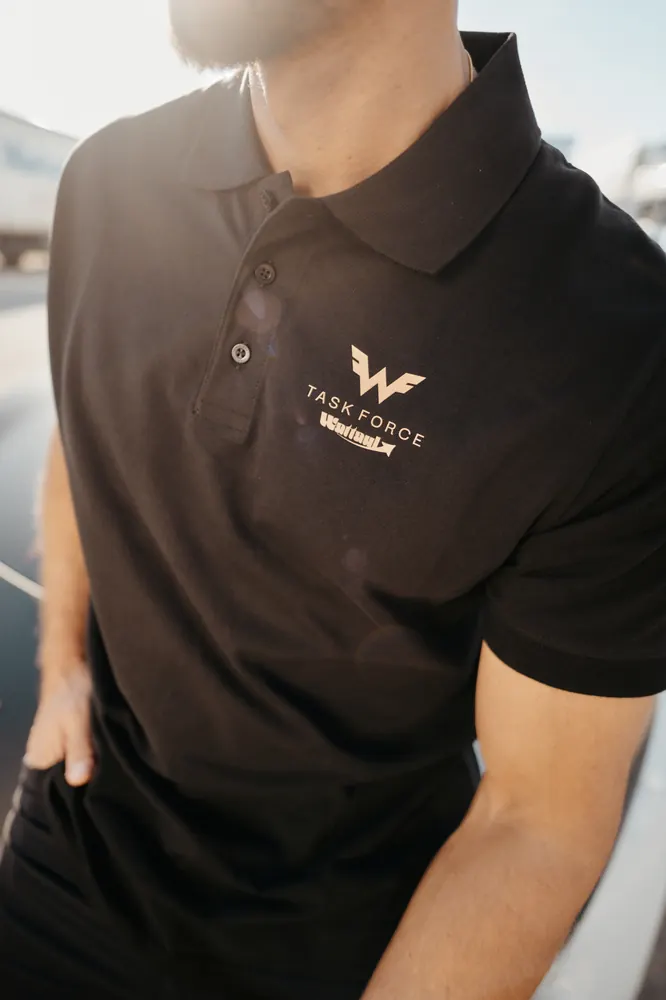 Taskforce-Logo auf dem schwarzen Poloshirt eines Mitarbeiters